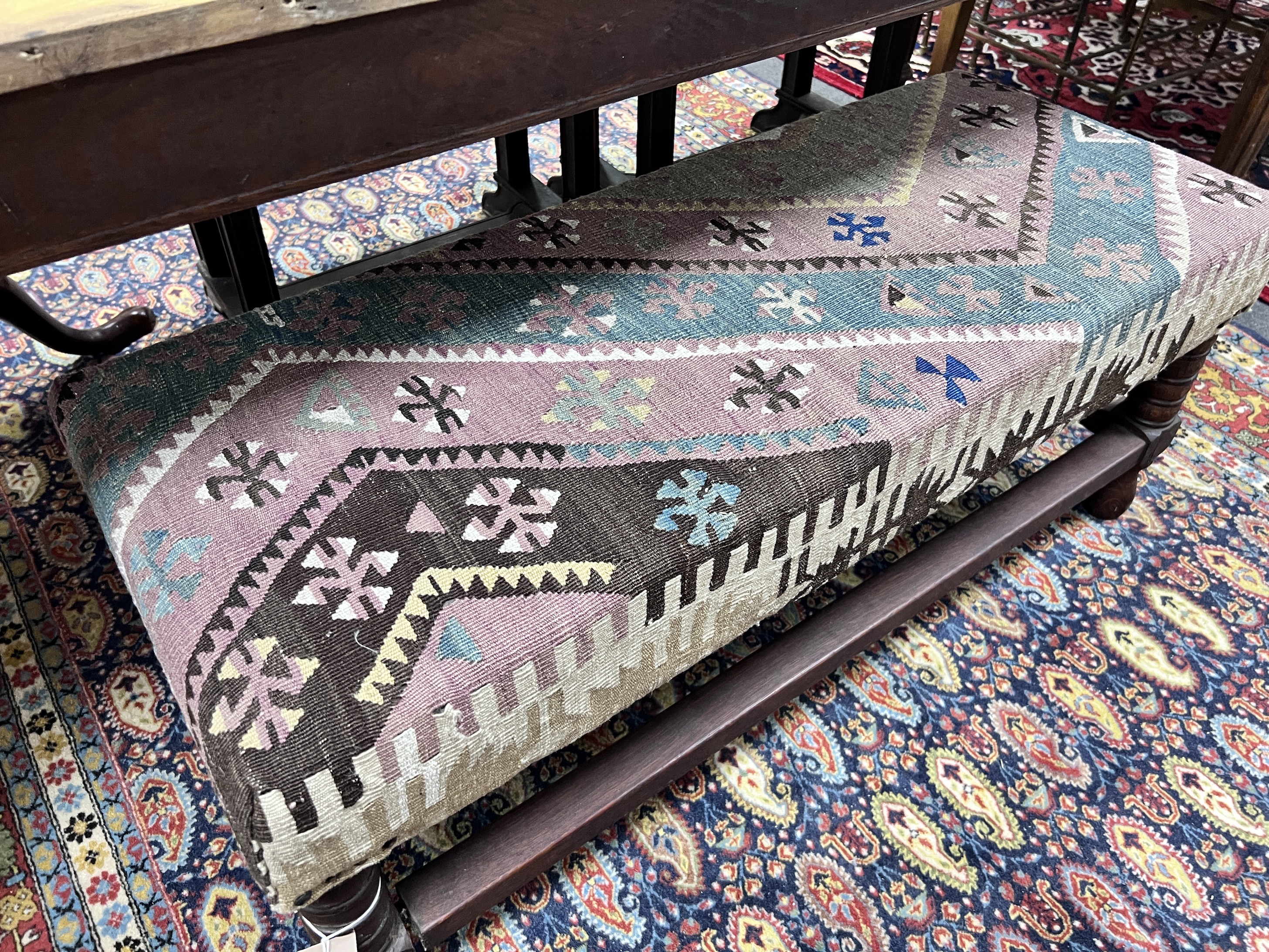 A 17th century style oak stool with contemporary Kilim upholstery, width 100cm